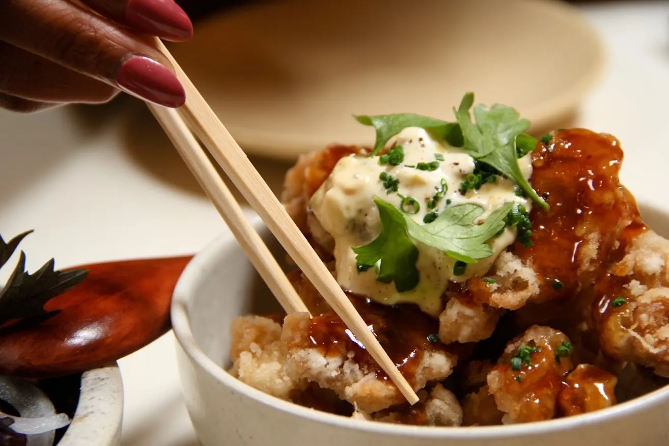 chopsticks reaching for a shared plate of fried chicken